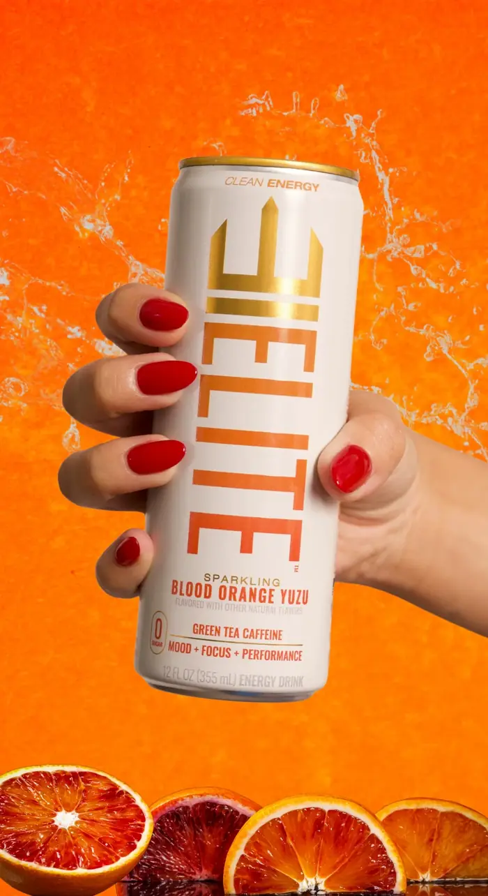 Hand holding a chilled ELITE Blood Orange Yuzu can amid a citrus splash